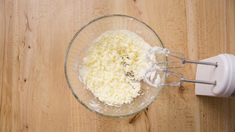 butter and sugar combined in glass mixing bowl next to electric mixer