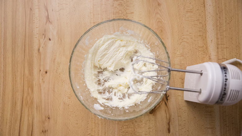 whipped frosting in mixing bowl next to electric mixer