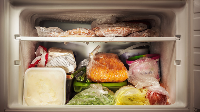 A kitchen freezer stocked with various kinds of frozen foods in bags and tubs