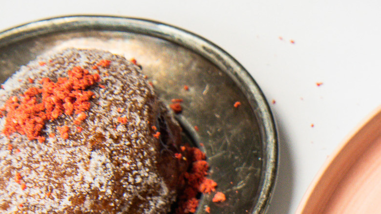 Five sugar-coated donuts on a pink plate with strawberries around them.