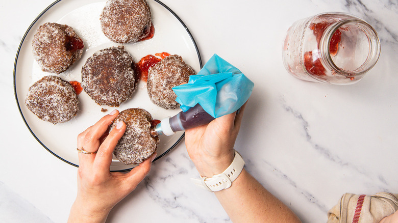 Filling donuts with jam.