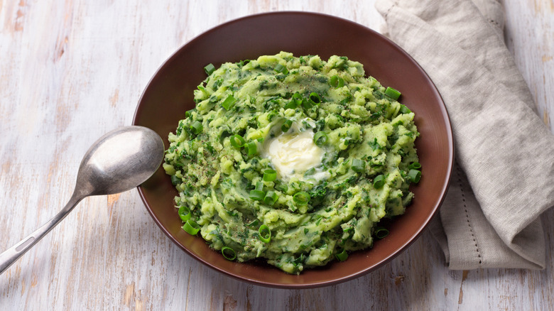 green mashed potato with spoon and pat of butter