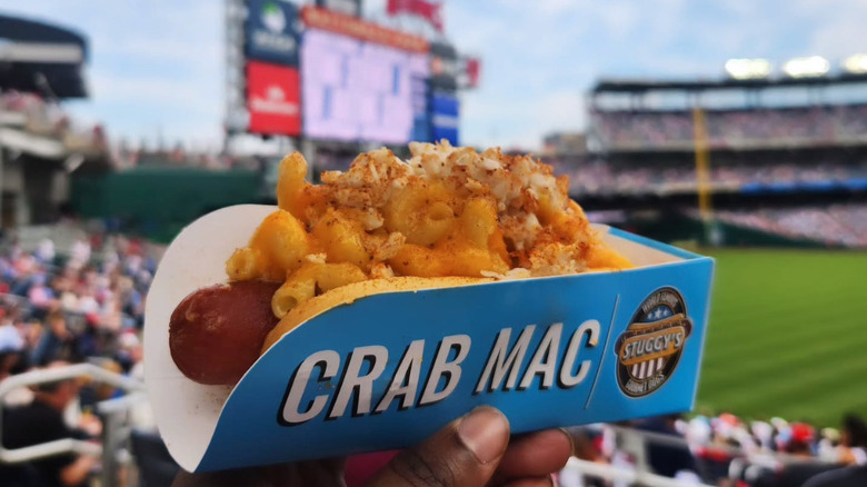 A hot dog topped with mac and cheese and crab meat