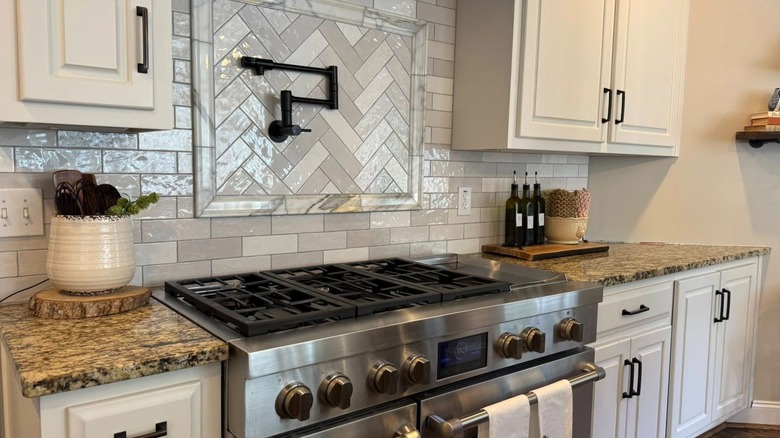 Kitchen with gray tile backsplash, white cabinets, and granite counters