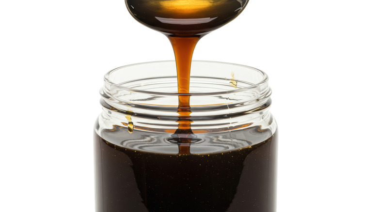 Spooning molasses from a jar against a white background