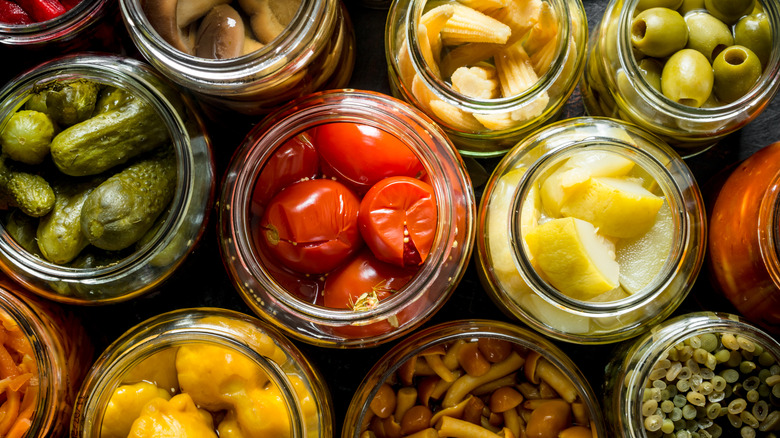 Top-down view of various pickled vegetables in open jars