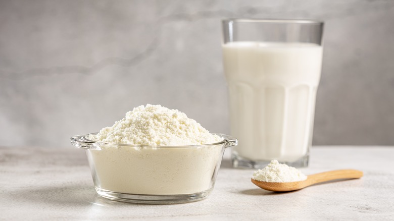 Bowl of powdered milk next to a glass of milk