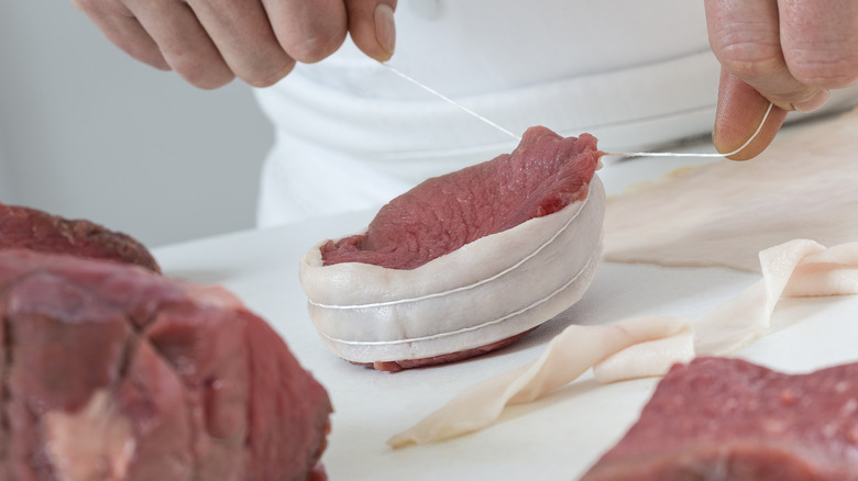 Chef barding meat for beef tournedos