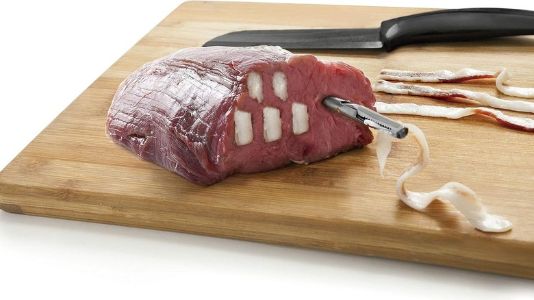 Large cut of meat larded with strips of fat on cutting board