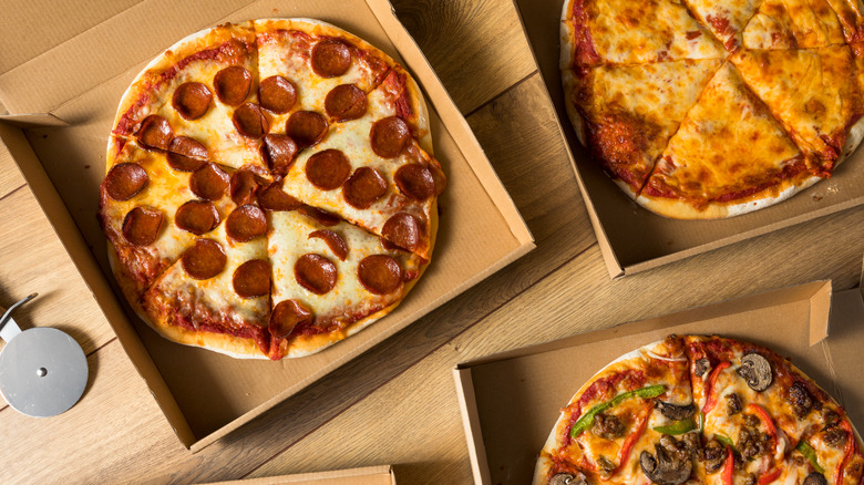 Several pizzas in cardboard takeout boxes