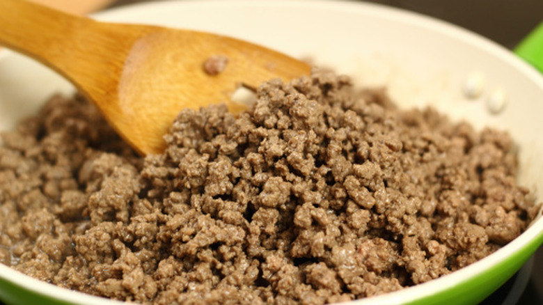 spatula moving ground beef in a pan