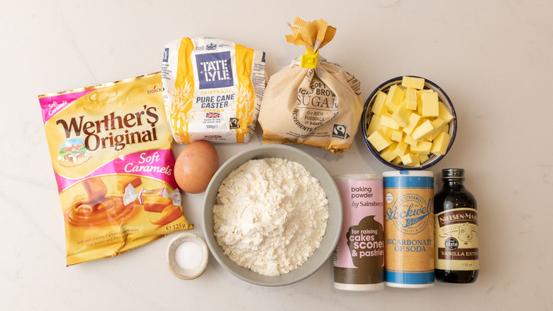 bag of soft caramels, bowl of flour, and other caramel cookie ingredients laid out