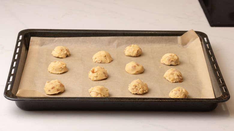 raw cookie dough scoops arranged on a lined baking sheet