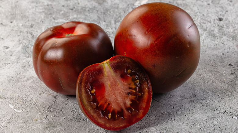 2 whole and one halved kumato, a very dark variety of tomato