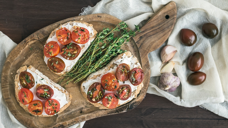 A person making a sandwich places sliced tomatoes