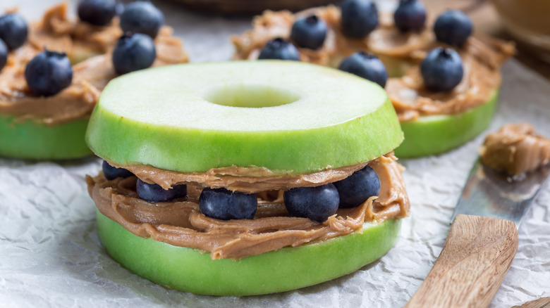 An apple sandwich with peanut butter and blueberries