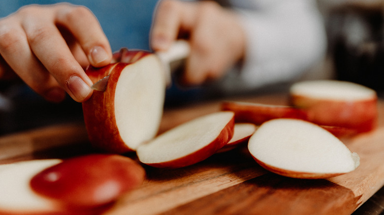 Someone slicing a red apple