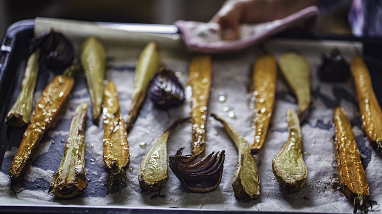 Plate of colorful root vegetable chips on wooden background with chips spilled