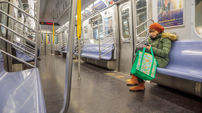 woman sitting on New York City subway with reusable grocery bag