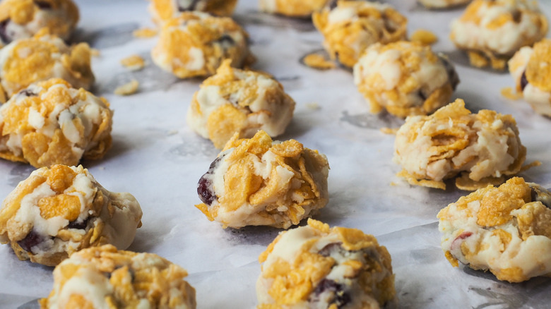Balls of cornflake cookie dough waiting to be baked on a tray