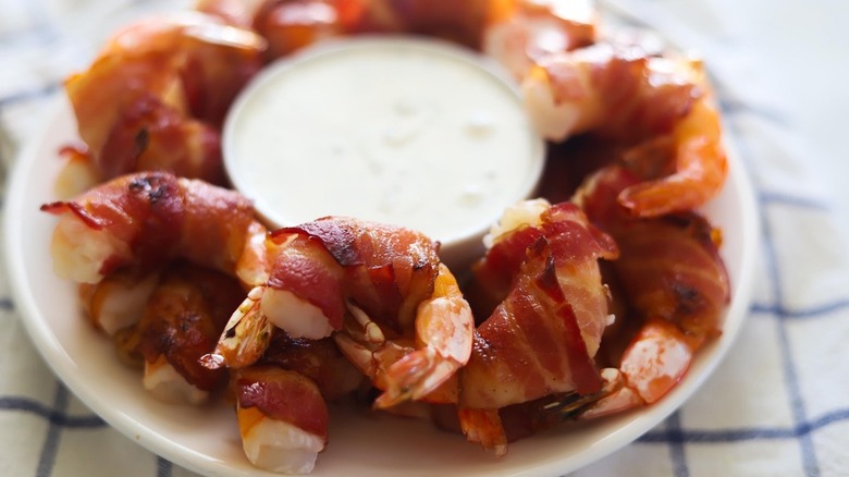 Tray of bacon-wrapped shrimp with dipping sauce 