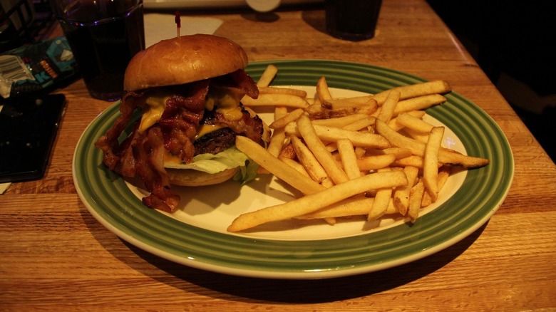 Bacon burger next to a helping of fries on a plate inside an Applebee's.