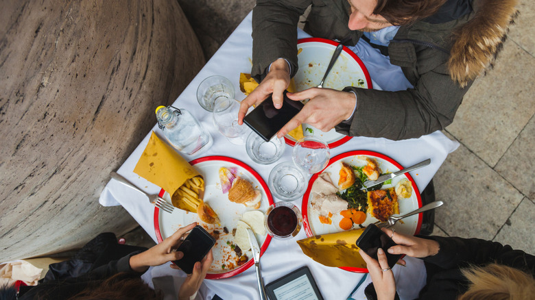 Brunch food on plates with diners on phones