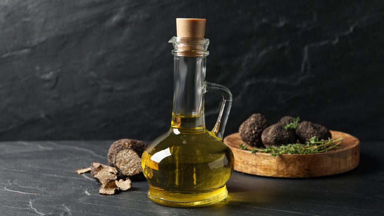 Oil in pitcher with truffles on plate behind