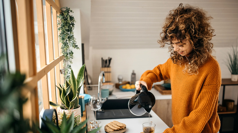 A woman pouring herself a cup of coffee in a small but modern kitchen