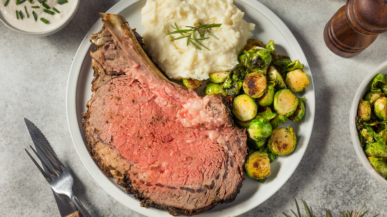 Plate of prime rib, mashed potatoes, and brussels sprouts.