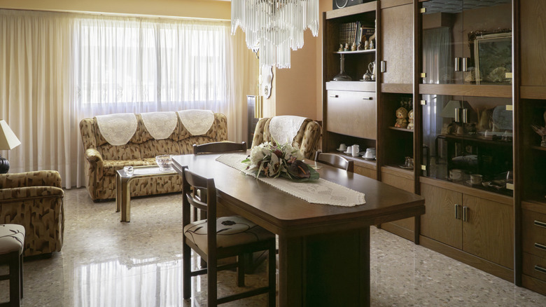 1980s-style dining room with pastel pink walls, large wooden dining table and cabinetry, and white chandelier