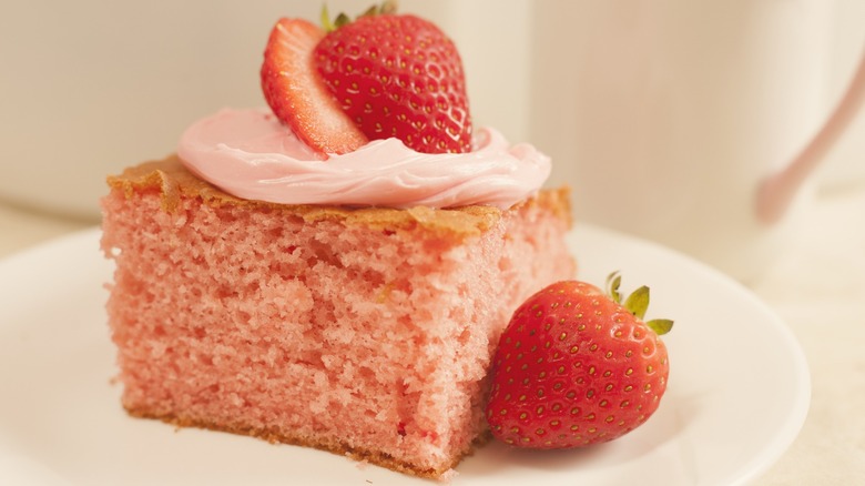 Closeup of a slice of strawberry cake garnished with strawberries