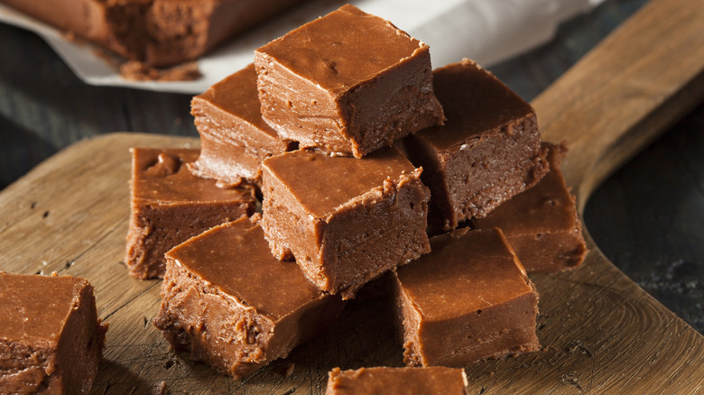 Squares of homemade chocolate fudge on a wooden cutting board