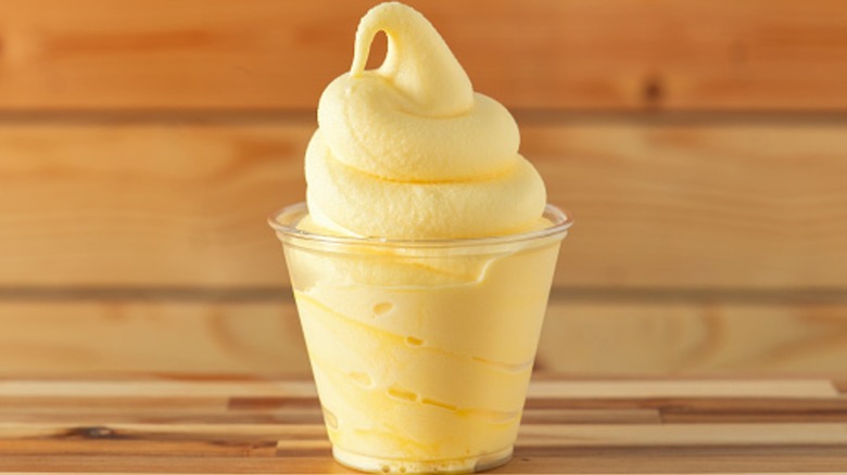 Dole whip in a plastic cup with wood background