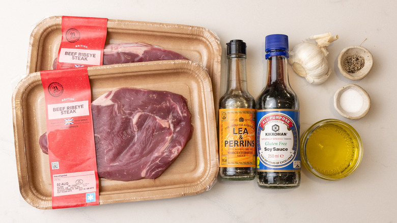 two packs of raw steak, bottles of soy sauce and Worcestershire sauce, and other 3-ingredient steak marinade ingredients laid out