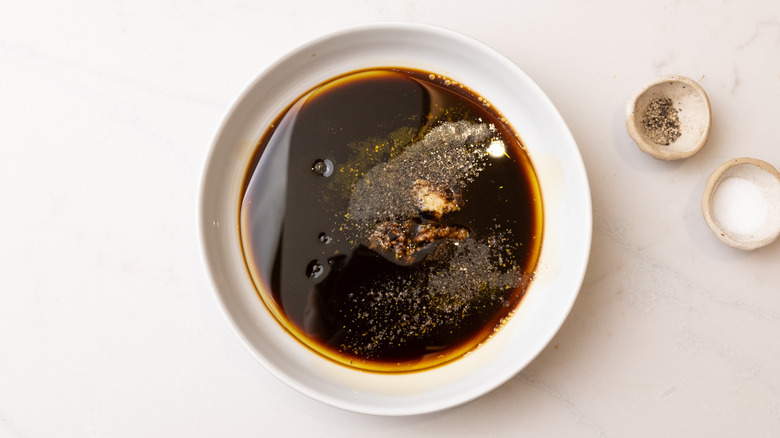steak marinade ingredients in bowl next to small dishes of seasoning