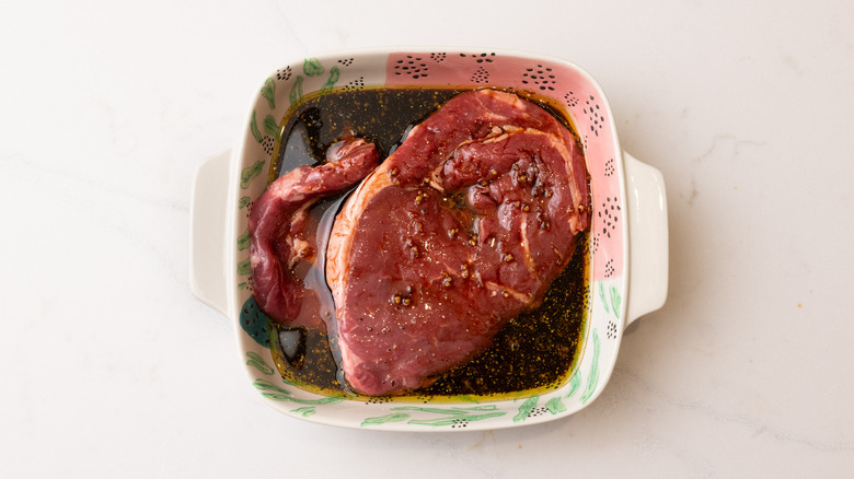aerial view of steaks marinating in bowl of marinade