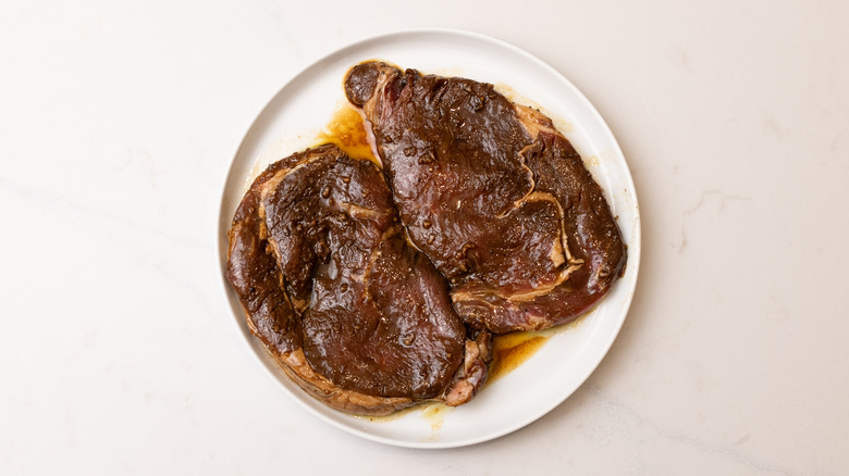 Two pieces of marinated steak on a white plate
