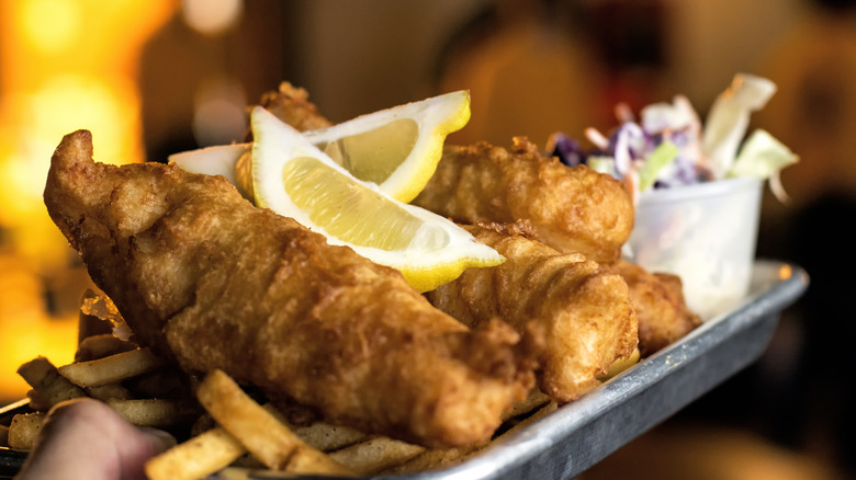 A person holds up a platter of fish and chips.