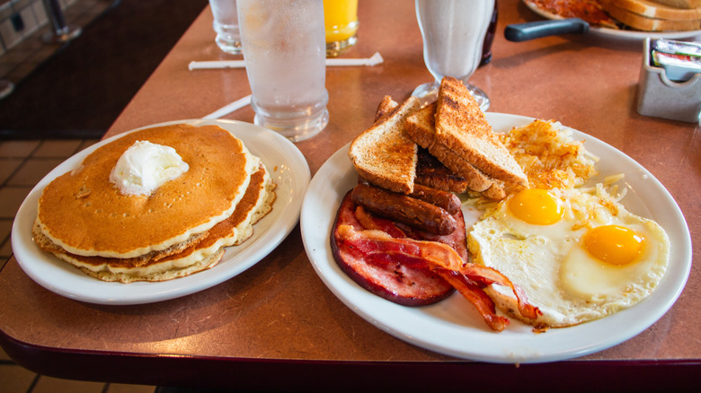 a diner breakfast of eggs, hash browns, ham, bacon, sausages, toast, and pancakes