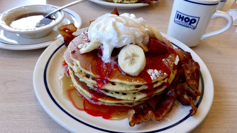 A stack of pancakes with strawberry bananas on top