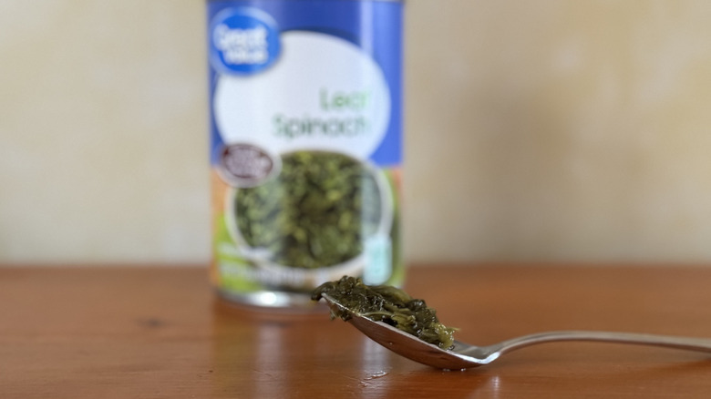 A can of Great Value spinach behind a spoonful of spinach