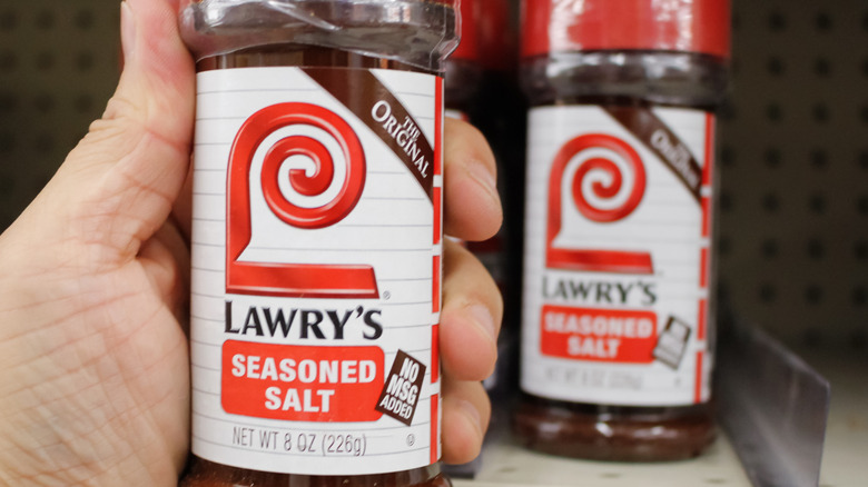 Someone holding a container of Lawry's seasoned salt with another on a shelf in the background