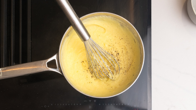 seasoned cornmeal mixture in saucepan with whisk inside over stovetop