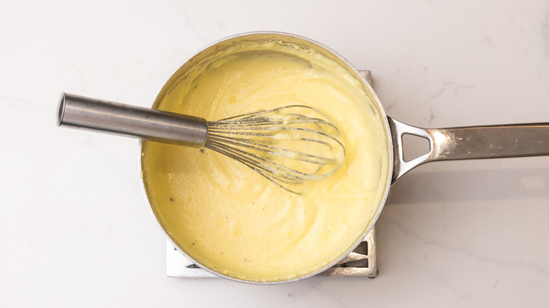 cornmeal mixture cooling in a saucepan on trivet with whisk in it