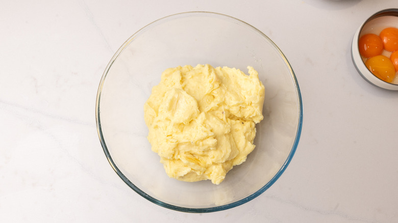 cornmeal mixture in a large glass bowl next to dish of four egg yolks