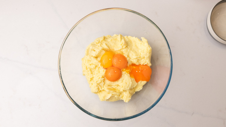 four egg yolks sitting on top of cornmeal in a glass bowl