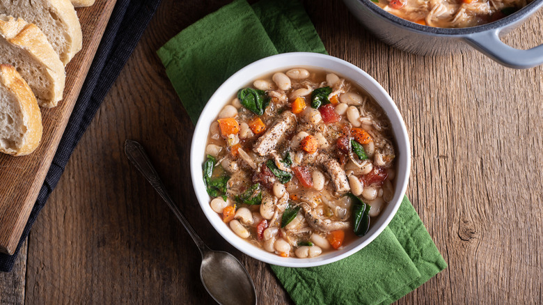 Overhead view of white bean soup with veggies and meat in a bowl