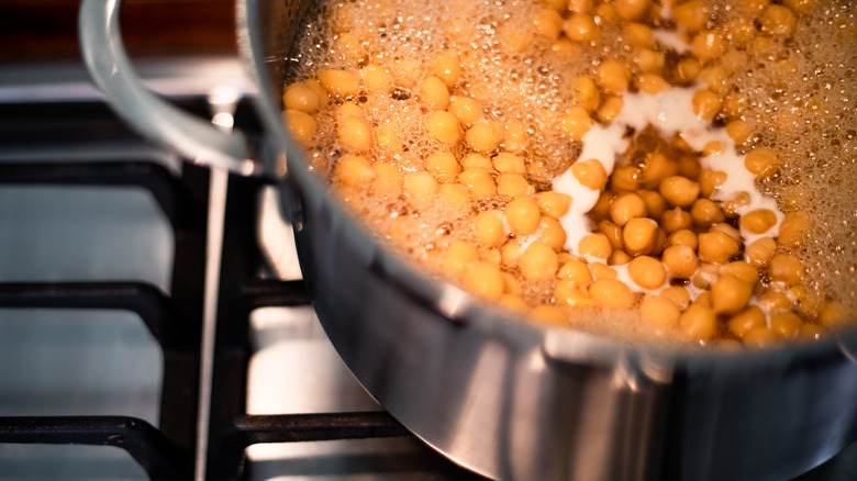 Overhead closeup view of garbanzo beans cooking in water in a pot