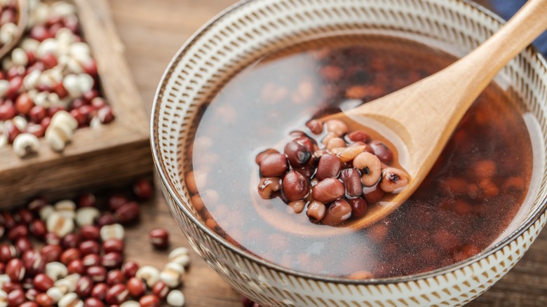 A spoon lifting a soup with Job's tears from a bowl